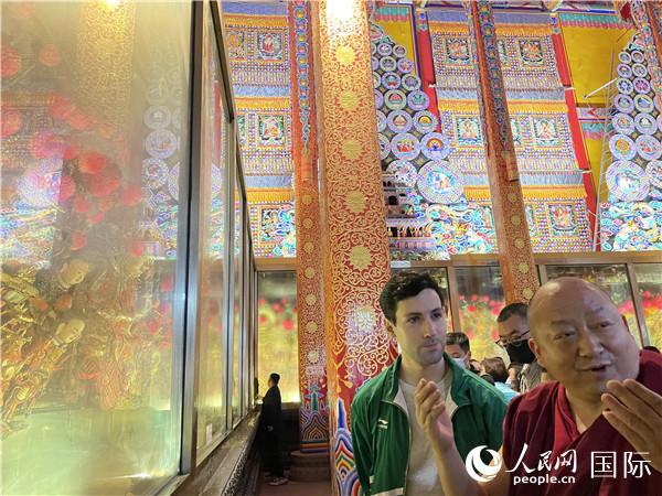 7月25日,省級非物質文化遺產(chǎn)項目塔爾寺酥油花的代表性傳承人朋措堅參(右)在塔爾寺酥油花館講解酥油花的制作過程。人民網(wǎng) 謝瑩攝