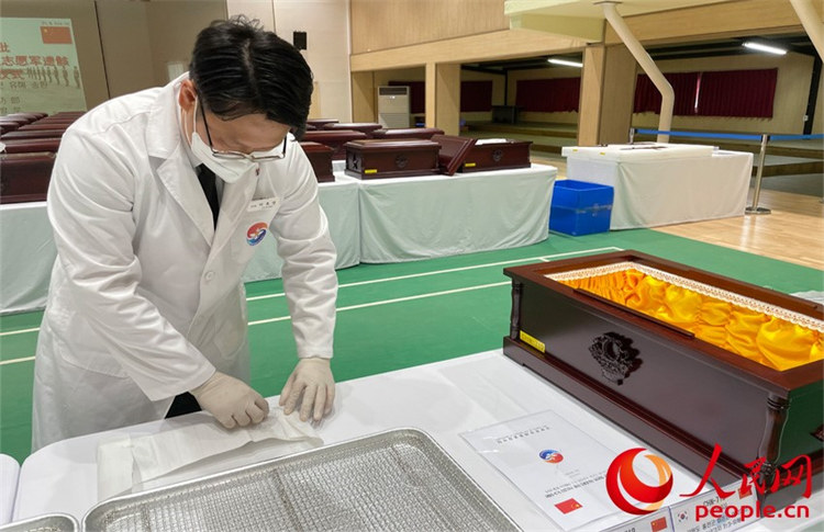 韓方遺骸發(fā)掘鑒識(shí)團(tuán)人員將遺骸放入棺槨。人民網(wǎng) 張悅攝