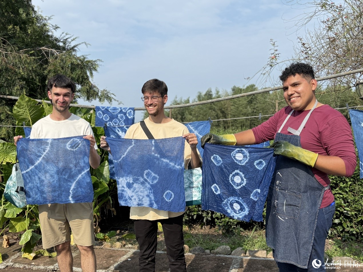 拉美國家媒體團(tuán)的記者們開心展示自己親手制成的藍(lán)染作品。人民網(wǎng)記者 朱虹攝