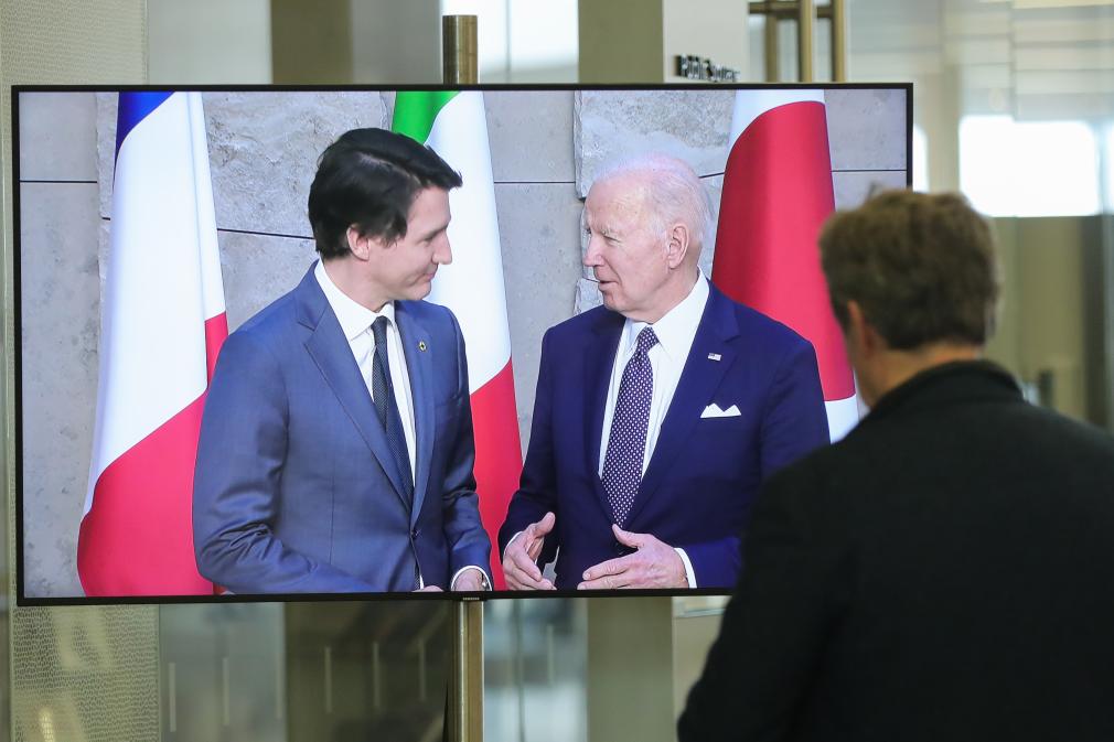 2022年3月24日，比利時(shí)布魯塞爾一名男子觀看屏幕上美國(guó)總統(tǒng)拜登（右）、加拿大總理特魯多出席七國(guó)集團(tuán)峰會(huì)合影儀式的畫面。（新華社記者鄭煥松攝）