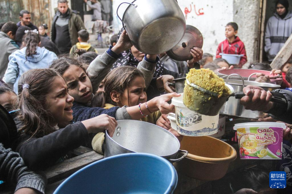 12月27日，巴勒斯坦人在加沙城領(lǐng)取救濟食物。新華社發(fā)（馬哈茂德·扎基攝）