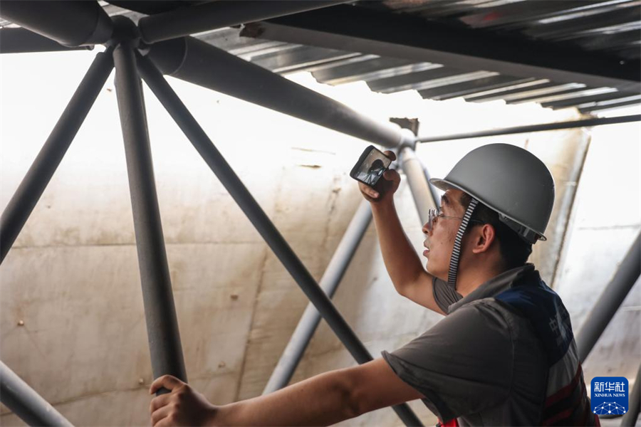 1月1日，在瓦努阿圖維拉港，中國地震局工程力學研究所副研究員柏文在一棟建筑的結構頂部網架位置記錄受損情況。新華社記者 龍雷 攝
