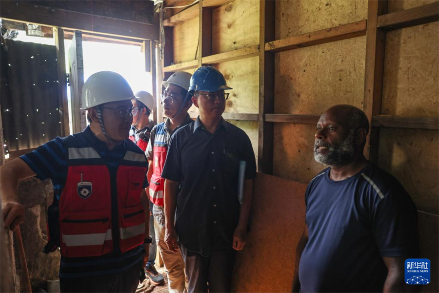 1月1日，在瓦努阿圖維拉港，中國地震局專家組成員向當(dāng)?shù)鼐用窳私夥课菔軗p情況。新華社記者 龍雷 攝