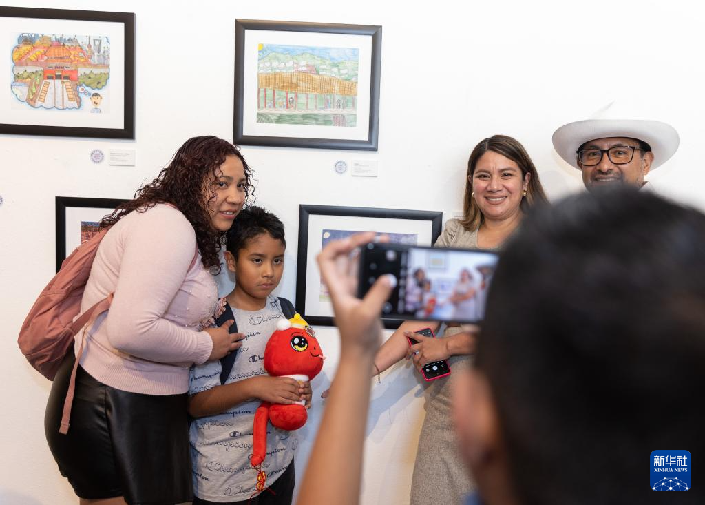 1月18日，在墨西哥首都墨西哥城舉行的第十一屆“我想象中的中國(guó)”兒童繪畫比賽活動(dòng)上，參賽者和家人手拿蛇年春節(jié)玩偶在畫作前留影。新華社記者 李夢(mèng)馨 攝