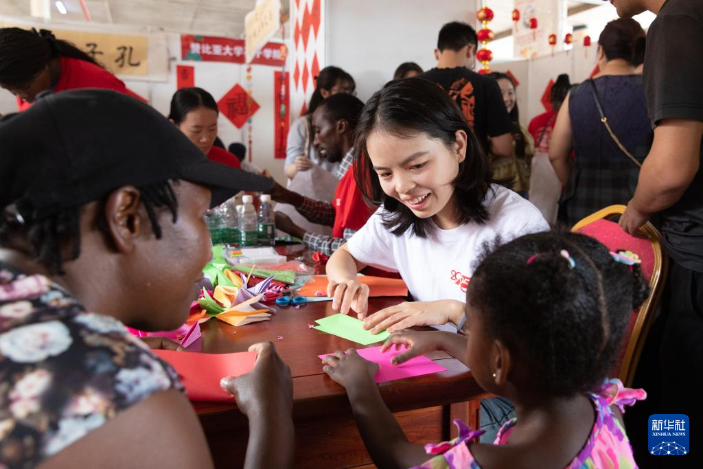 1月19日，在贊比亞首都盧薩卡舉行的春節(jié)廟會(huì)活動(dòng)上，一名贊比亞大學(xué)孔子學(xué)院的老師教一名小朋友折千紙鶴。新華社記者 彭立軍 攝