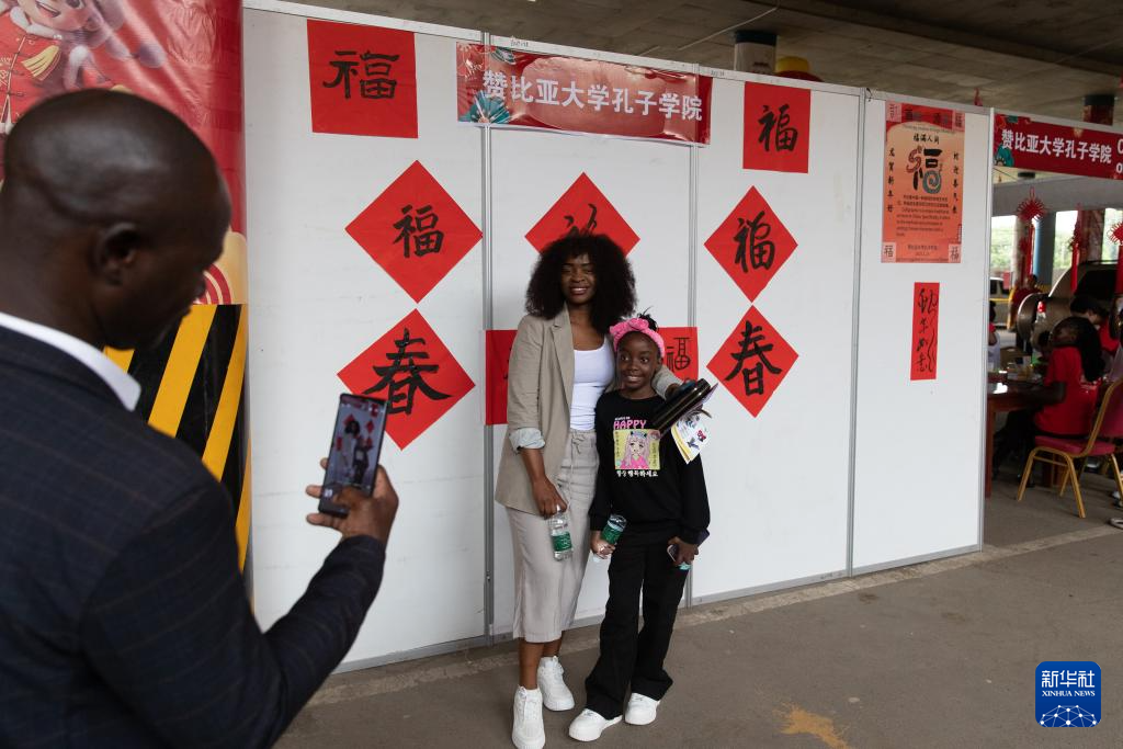 1月19日，在贊比亞首都盧薩卡舉行的春節(jié)廟會(huì)活動(dòng)上，人們在贊比亞大學(xué)孔子學(xué)院的展區(qū)前合影留念。新華社記者 彭立軍 攝