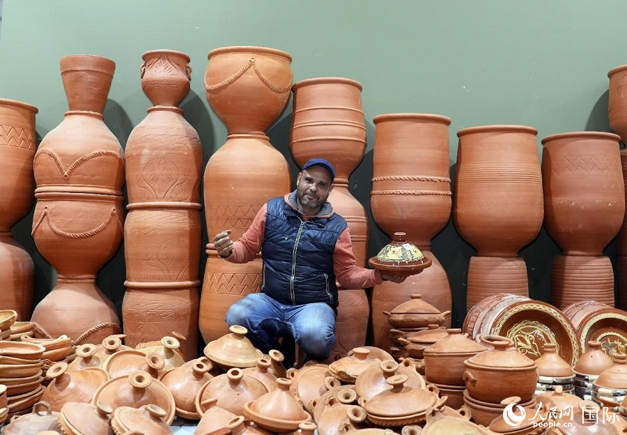塔吉鍋是摩洛哥傳統(tǒng)美食，類似中國的瓦罐燉肉。鍋用陶土制成，鍋蓋如塔。圖為一名商販展示塔吉鍋。人民網(wǎng)舒艾卜·布拉達攝