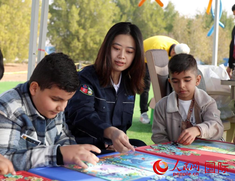 中方員工帶著伊方員工孩子玩拼圖。人民網(wǎng) 伊納斯·易卜拉欣攝