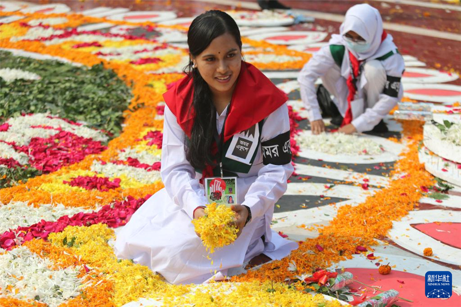 2月21日，在孟加拉國首都達(dá)卡的語言烈士紀(jì)念碑前，一名志愿者正在布置鮮花。新華社發(fā)（哈比卜·拉赫曼攝）