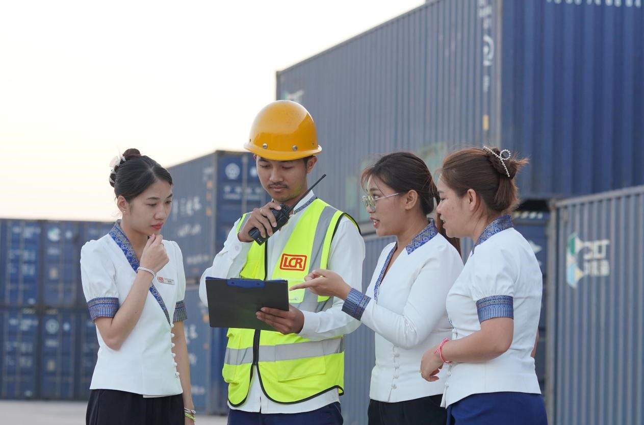 萬象南站貨運值班員陳尼啦（左一）與同事在一起討論工作。老中鐵路有限公司供圖