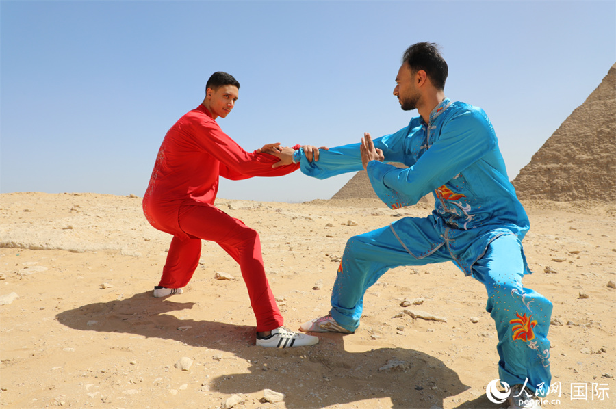 圖為埃及太極拳習(xí)練者在埃及吉薩省金字塔前練習(xí)太極拳動(dòng)作，在一招一式間用心感悟古老的東方智慧。 人民網(wǎng) 欣德·法蒂·穆罕默德攝