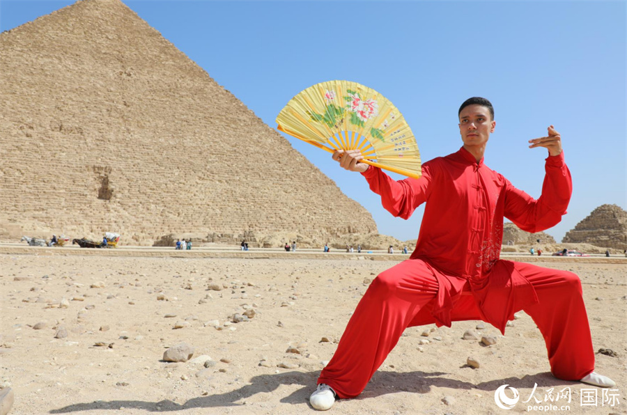 圖為埃及太極拳習(xí)練者在埃及吉薩省金字塔前練習(xí)太極拳動(dòng)作，在一招一式間用心感悟古老的東方智慧。 人民網(wǎng) 欣德·法蒂·穆罕默德攝
