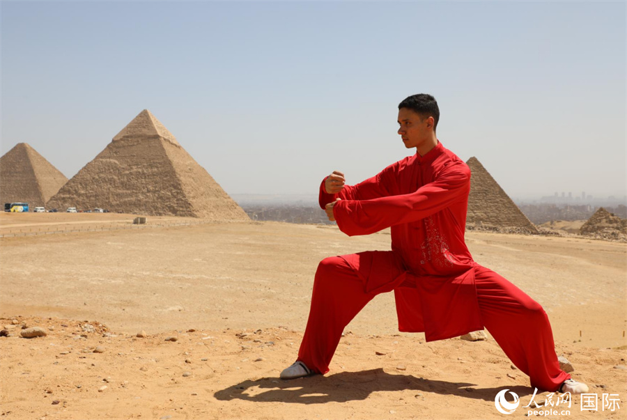圖為埃及太極拳習(xí)練者在埃及吉薩省金字塔前練習(xí)太極拳動(dòng)作，在一招一式間用心感悟古老的東方智慧。 人民網(wǎng) 欣德·法蒂·穆罕默德攝