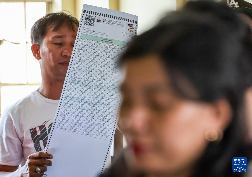 5月12日，在菲律賓奎松市，一名選民在投票站內檢查自己的選票。新華社發(fā)（烏馬利攝）