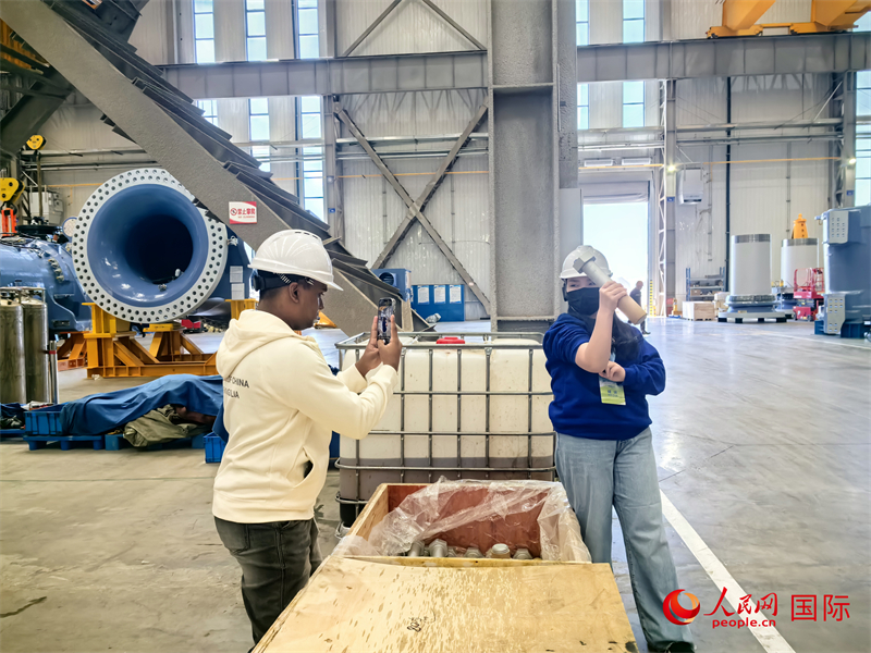 外媒記者掂量廠房內(nèi)的巨型螺栓。人民網(wǎng) 楊春燕攝