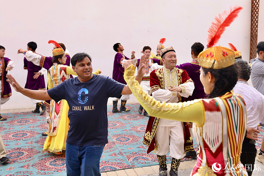 5月24日，上合組織國家青年文化交流營的青年們走進龜茲小巷，感受新疆生活。以上圖為龜茲小巷內，中外青年們在一起跳舞。人民網記者 蔣雨師攝