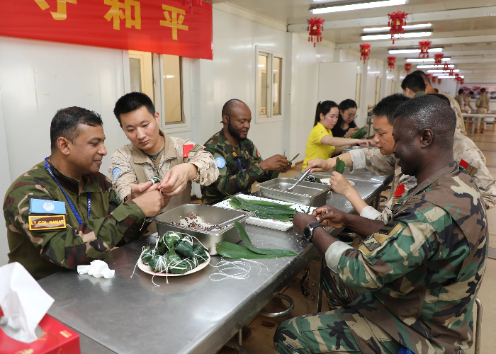 圖為我維和官兵和外軍友人一起包粽子。張曉昆攝