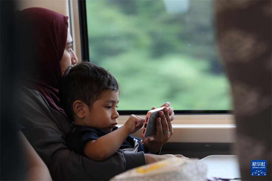 6月19日，一名乘客帶孩子坐在行駛中的雅萬高鐵車廂內(nèi)。新華社記者 岑云鵬 攝