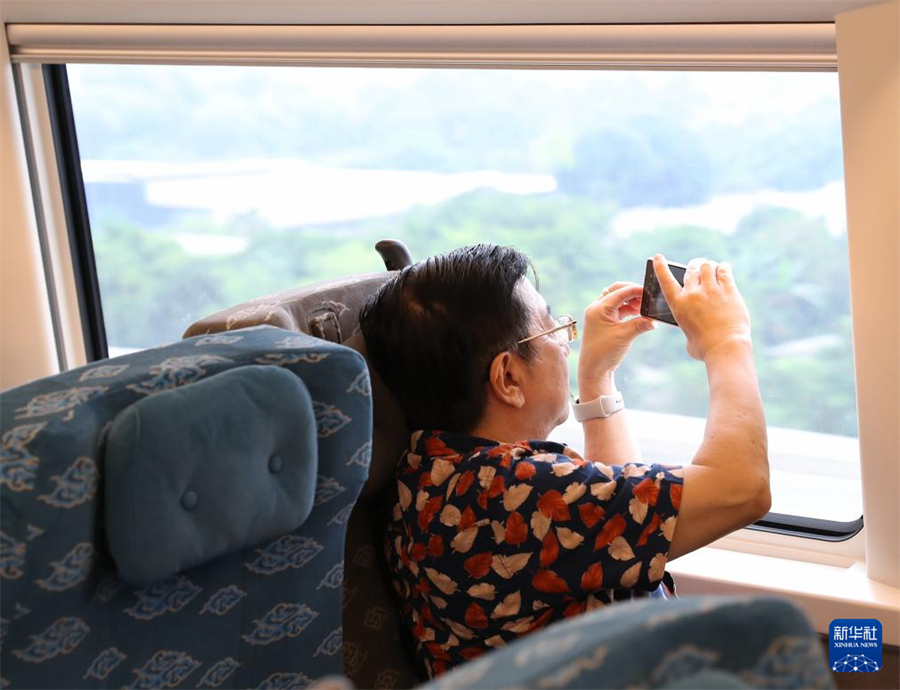 6月19日，一名乘客在行駛中的雅萬高鐵車廂內(nèi)拍攝沿途風景。新華社記者 岑云鵬 攝