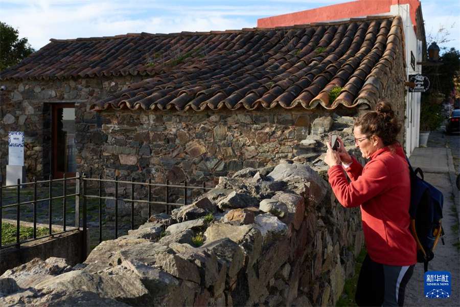 6月25日，一名女子在烏拉圭科洛尼亞的老城區(qū)拍攝歷史建筑。新華社記者 孟鼎博 攝