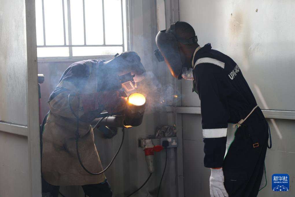 6月16日，在烏干達基貢巴石油學院，兩名學員在焊接工位進行練習。新華社發(fā)（中石化供圖）