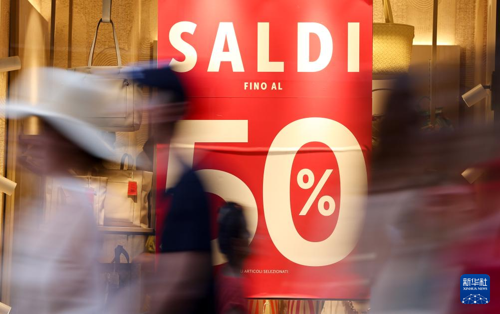 7月5日，在意大利羅馬，人們經(jīng)過(guò)一處商店櫥窗。新華社記者 李京 攝