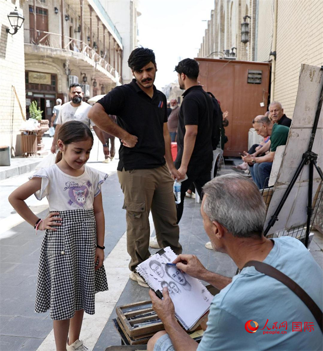一名街頭藝術(shù)家在給一名小女孩畫像。人民網(wǎng)伊納斯·易卜拉欣攝