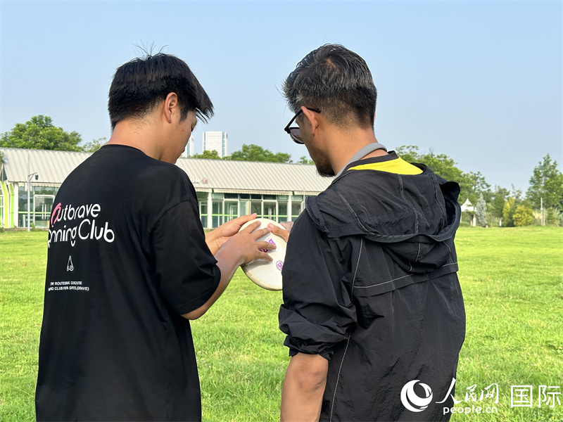 人民網(wǎng)外籍專家舒克里（右）學(xué)習(xí)擲準(zhǔn)飛盤動作。 人民網(wǎng) 孫書宇攝