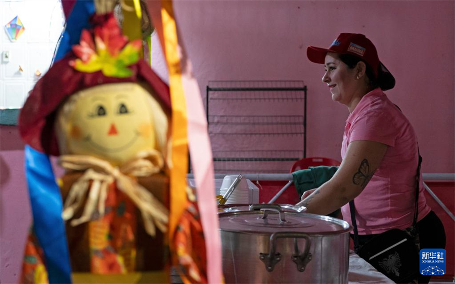 7月19日，在巴西里約熱內盧的曼吉尼奧斯社區(qū)，一名女子為“豐收節(jié)”活動的參與者準備食物。新華社記者 王天聰 攝