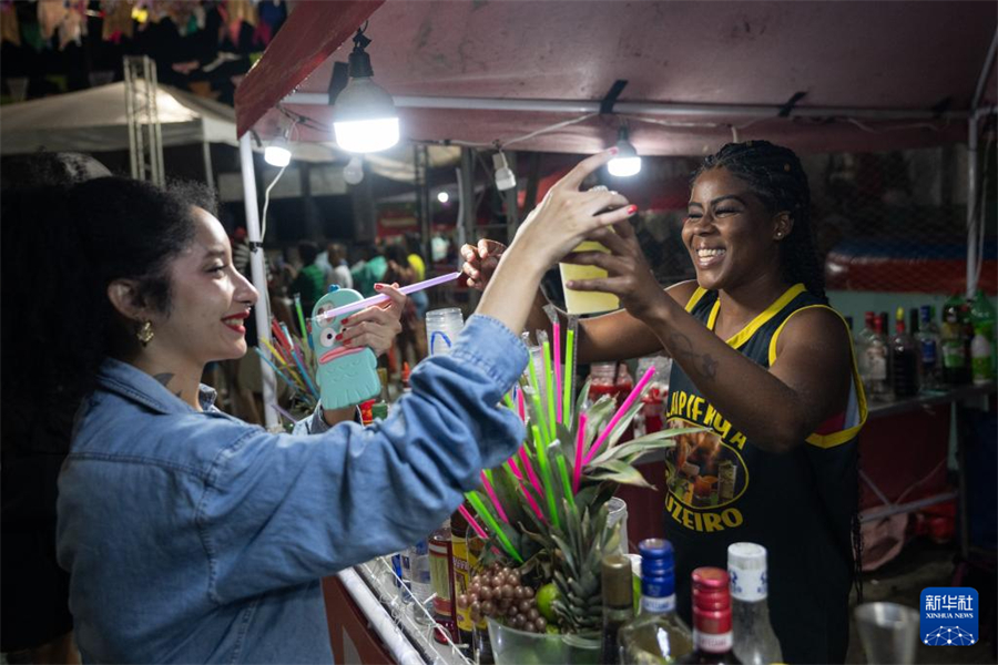 7月19日，在巴西里約熱內(nèi)盧的曼吉尼奧斯社區(qū)，顧客在“豐收節(jié)”活動的一處攤位上購買飲品。新華社記者 王天聰 攝