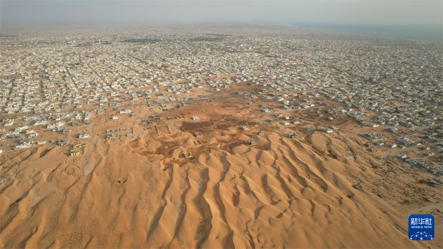 這是6月17日在毛里塔尼亞首都努瓦克肖特拍攝的沙丘和城市景觀（無人機(jī)照片）。新華社記者 司源 攝