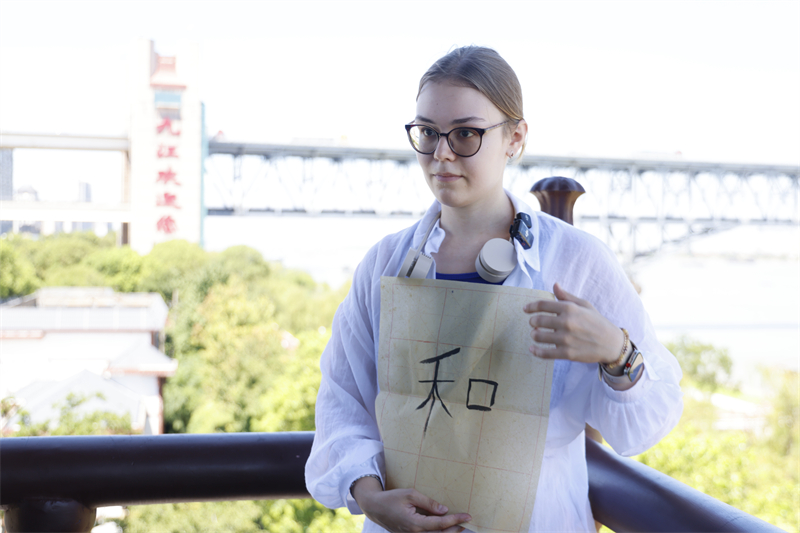 一名俄羅斯青年在琵琶亭展示自己的書(shū)法作品。九江市委宣傳部供圖