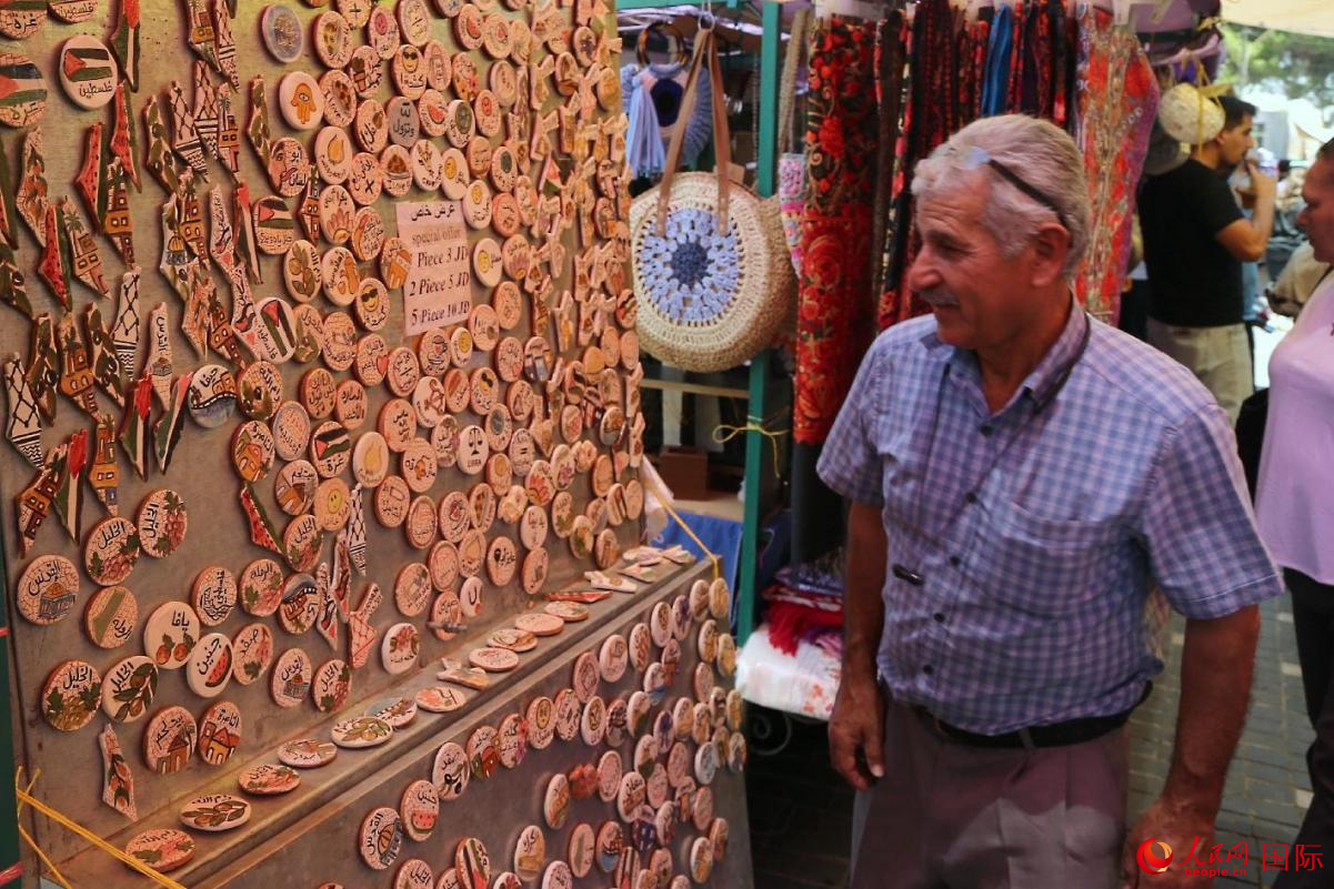 一位民眾走過售賣紀(jì)念品的攤位。人民網(wǎng) 納達(dá)爾·達(dá)烏德攝