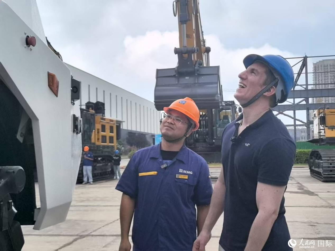 工作人員正在為人民網(wǎng)外籍專家介紹徐工無人電動礦卡ZNK95。人民網(wǎng)記者 鐘文興攝