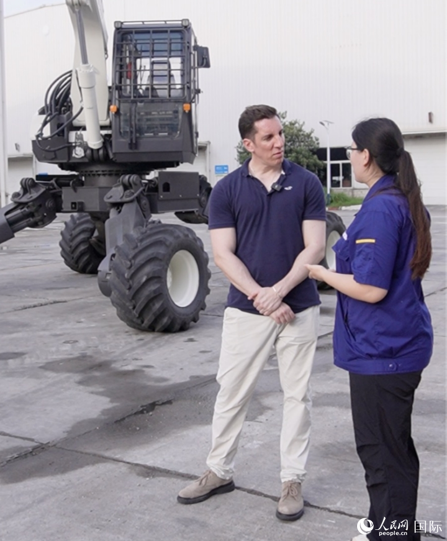 工作人員為人民網(wǎng)外籍專家介紹步履式挖掘機(jī)“鋼鐵螳螂”。人民網(wǎng) 喻亮攝