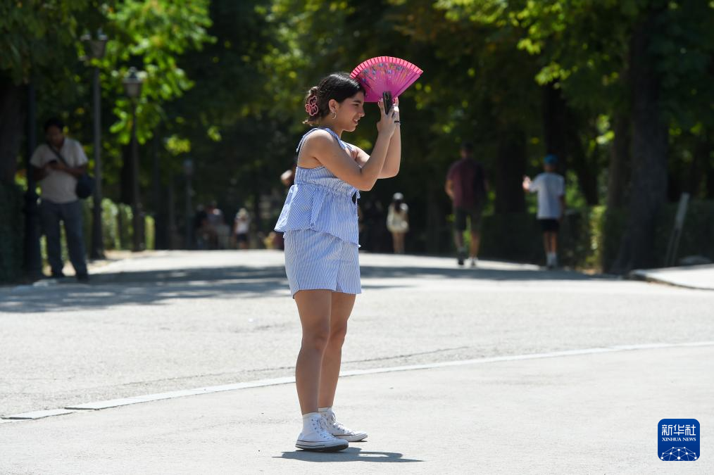 8月4日，一名女子在西班牙馬德里的公園內(nèi)用扇子遮陽(yáng)。新華社發(fā)（古斯塔沃·巴連特?cái)z）