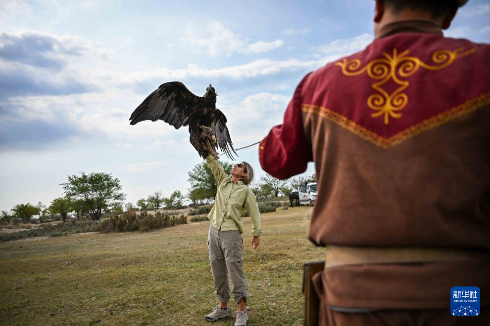 8月16日，在吉爾吉斯斯坦喬爾蓬阿塔附近，一名外國游客體驗訓(xùn)練獵鷹。新華社記者 李任滋 攝