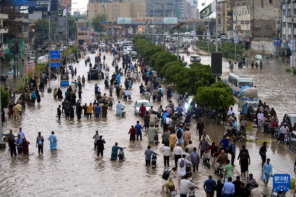 8月19日，在巴基斯坦南部港口城市卡拉奇，當(dāng)?shù)鼐用裨诒┯赀^后涉水出行。新華社發(fā)
