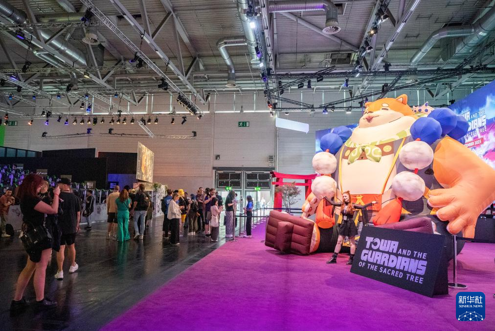 8月20日，在德國(guó)科隆，一名女子在2025年科隆國(guó)際游戲展上與模型合影。新華社記者 張帆 攝