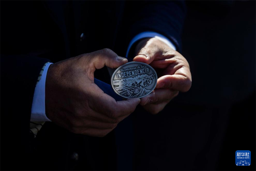 8月25日，在烏拉圭南部城市佛羅里達舉行的烏拉圭宣告獨立200周年紀念活動上，一名參加者展示獨立200周年的紀念章。新華社發(fā)（烏拉圭總統(tǒng)府供圖）