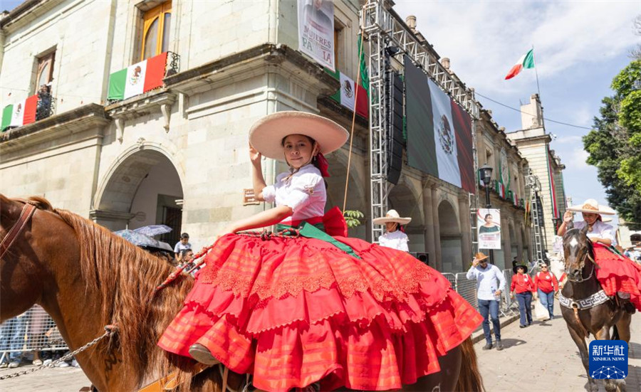 9月16日，在墨西哥瓦哈卡州的瓦哈卡市中心，身著傳統(tǒng)民族服裝的女孩騎馬參加獨立日慶?；顒印Ｐ氯A社記者 李夢馨 攝