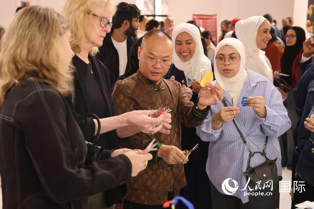 觀眾向中國(guó)師傅學(xué)習(xí)剪紙。人民網(wǎng)記者 張志文攝