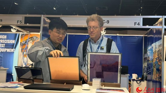 中國企業(yè)鶉火光電工作人員向歐美客戶展示該企業(yè)研發(fā)制造的鈣鈦礦電池。人民網(wǎng)記者 顏歡攝