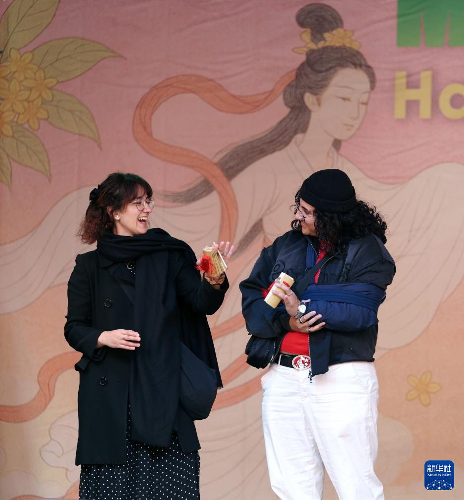 10月5日，當(dāng)?shù)孛癖娫谟?guó)倫敦舉行的中秋節(jié)慶?；顒?dòng)上體驗(yàn)打快板。新華社記者 李穎 攝