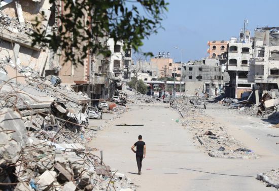 10月9日，在加沙地帶北部杰巴利耶，一名男子從建筑廢墟旁走過。新華社發(fā)（阿卜杜勒拉赫曼·薩拉馬攝）