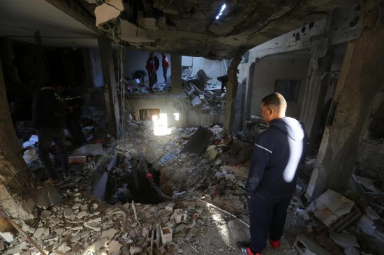 12月16日，在加沙地帶中部努賽賴特難民營(yíng)，人們查看以軍襲擊后的建筑廢墟。新華社發(fā)（里澤克·阿卜杜勒賈瓦德攝）