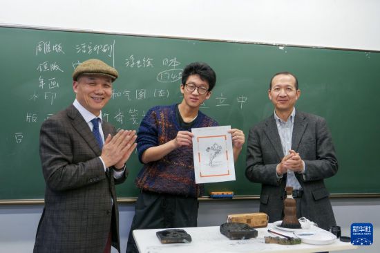 12月19日，在日本東京都的中央大學，一名大學生展示自己制作的木版水印畫。新華社發(fā)