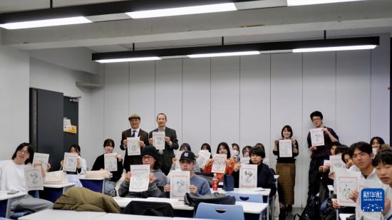 12月19日，在日本東京都的中央大學，學生們舉著自己制作的木版水印畫合影。新華社發(fā)