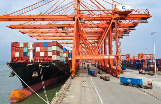 在廣西北部灣港欽州港區(qū)碼頭，吊車為貨輪卸載集裝箱（10月20日攝，無(wú)人機(jī)照片）。新華社記者李賀攝