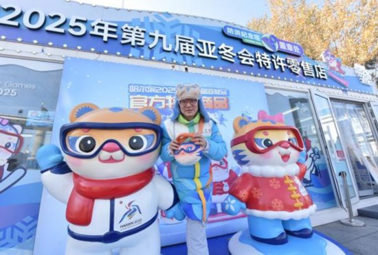 2024年10月29日，哈爾濱，“雙奧”志愿者張文全在2025年第九屆亞冬會特許零售店門口拍照留念。受訪者供圖